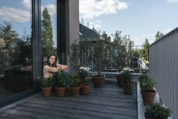 smiling woman relaxing on balcony surrounded by pl 2024 09 18 21 52 26 utc 1 1